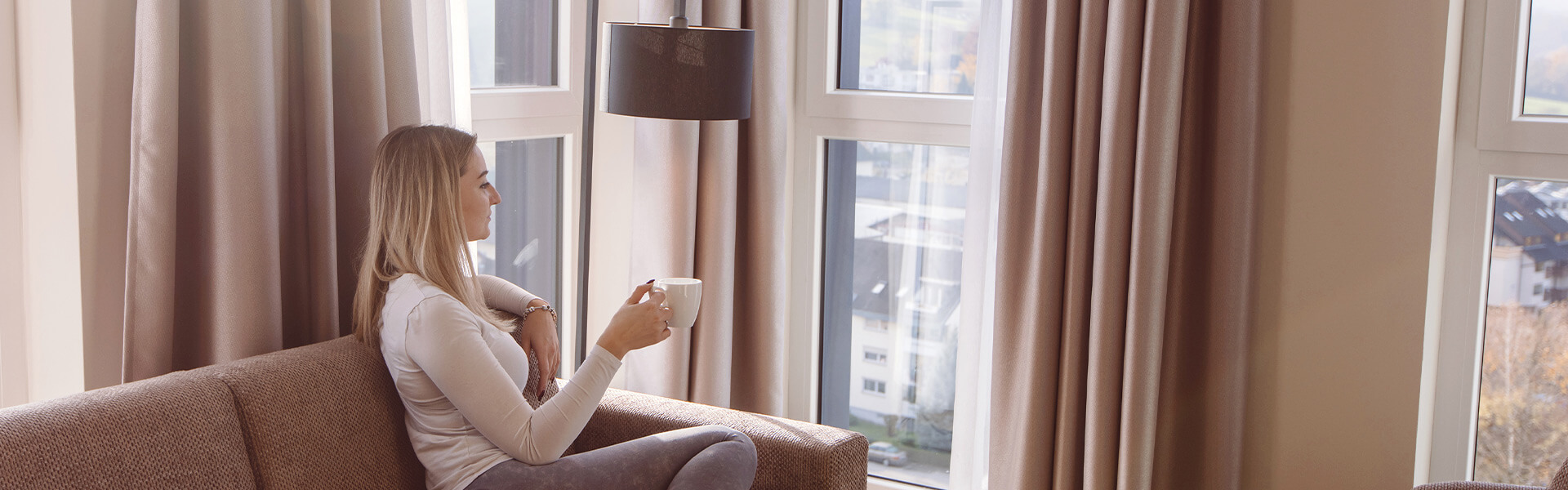 Ansicht auf eine Frau mit einer Teetasse auf einem Sofa in einem Hotelzimmer des Hotels Libertas Elements Pure