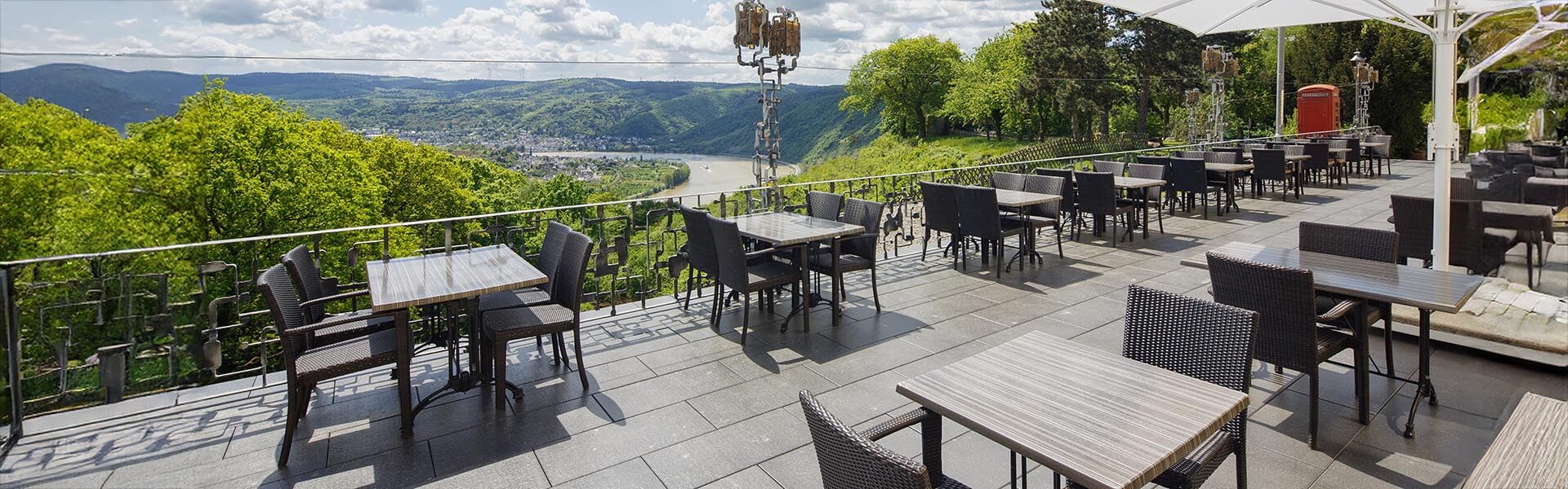 Ansicht der Terrasse des Hotel Jakobsberg mit Flussbett, Bergen und Stadt im Hintergrund