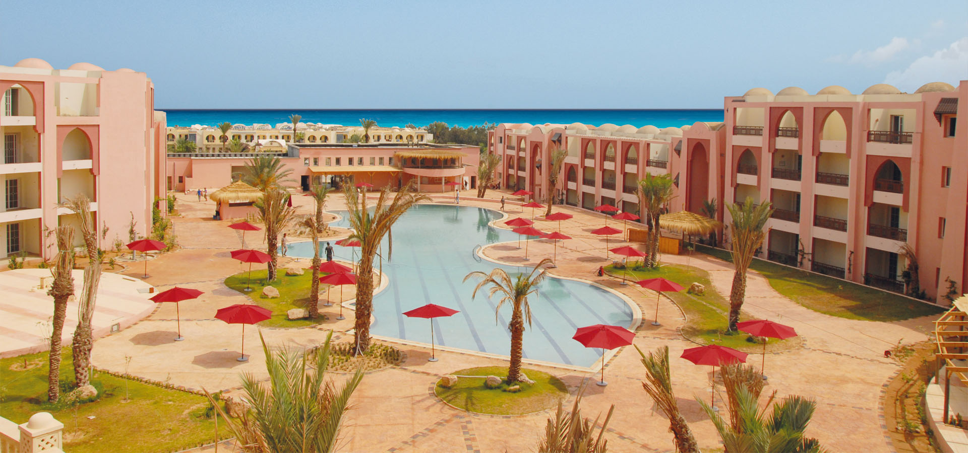 Außenansicht der Hotelanlage Lella Meriam mit Pool, Palmen und dem Meer im Hintergrund