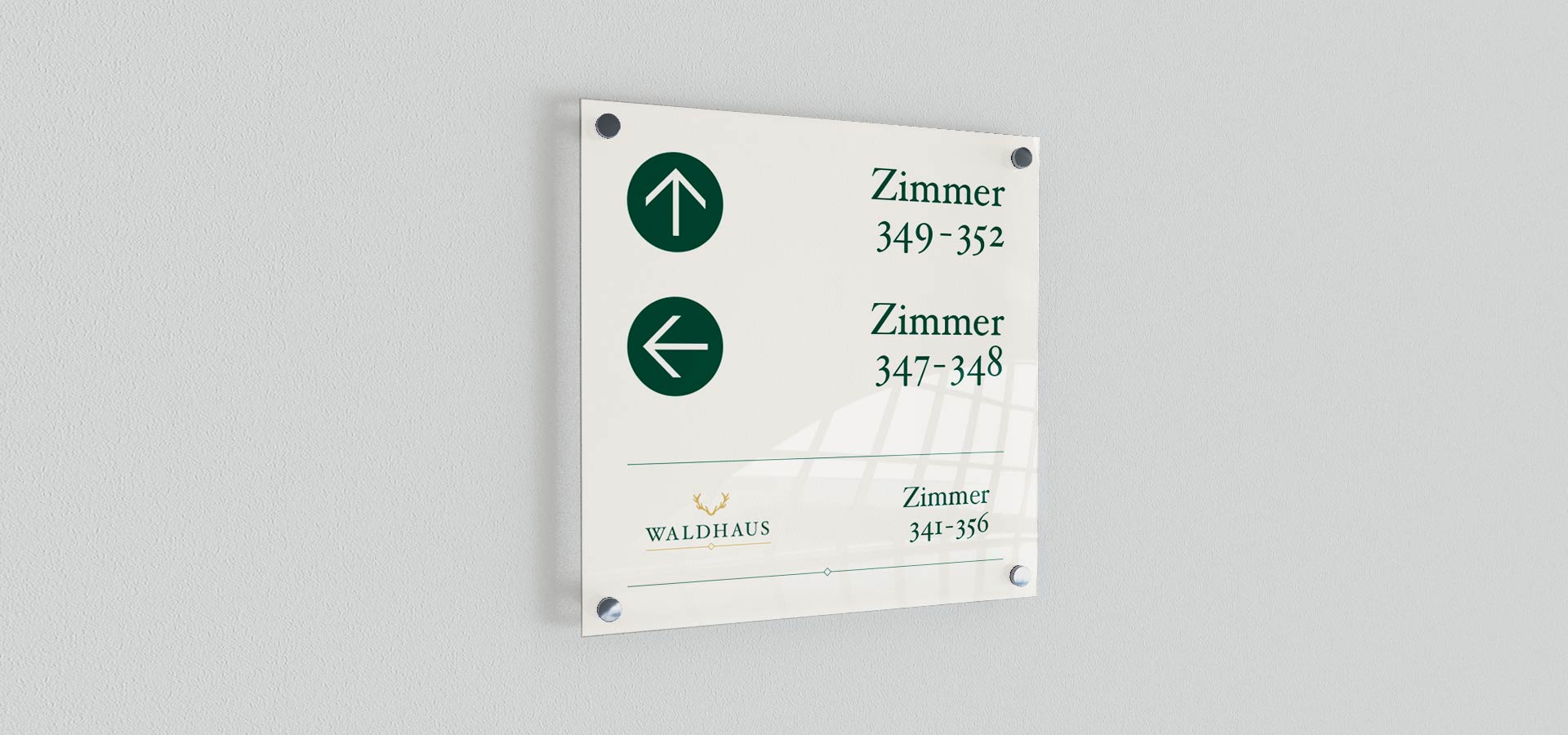 Ansicht auf ein Leitsystemschild im Corporate Design des Hotels Saigerhöh auf einer grauen Wand angebracht