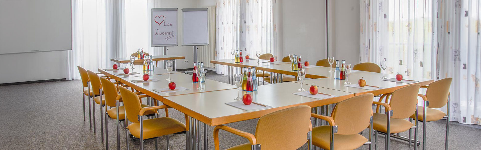 Ansicht auf den Tagungsraum mit gedeckten Tagungstischen und zwei Whiteboards