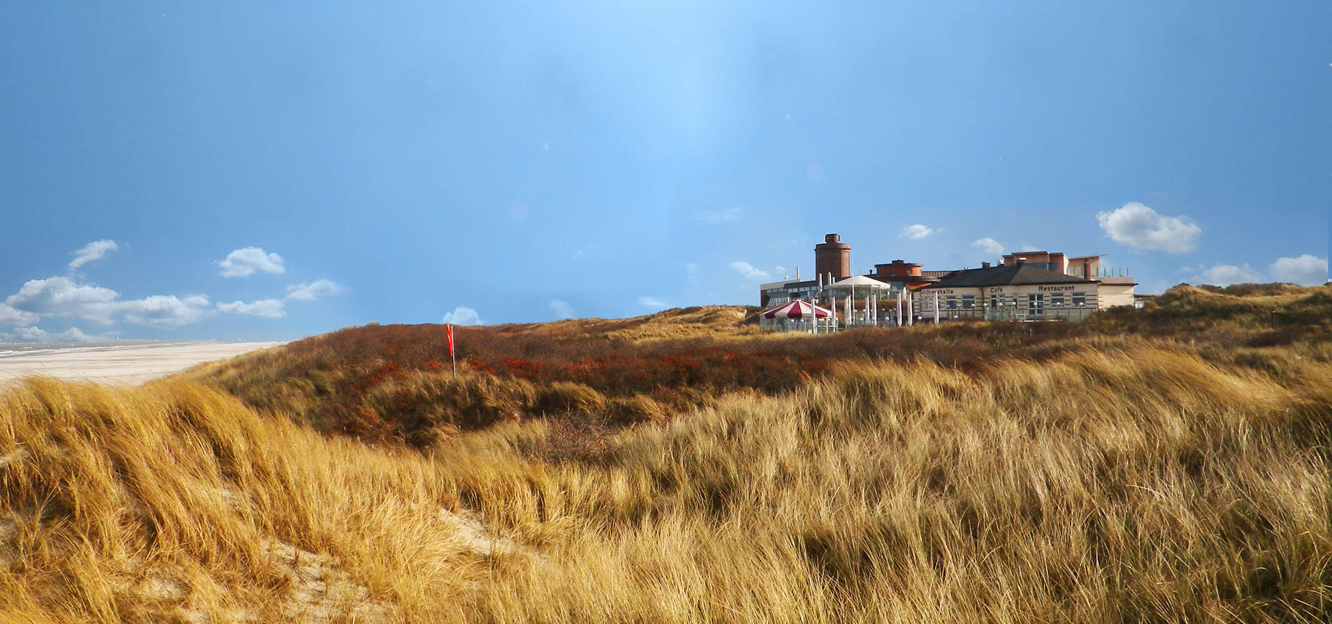 Außenansicht auf das Restaurant Strandhalle Juist mit Dünenlandschaft