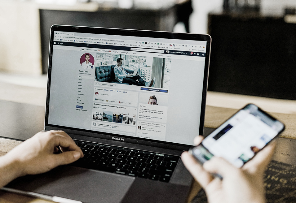 Laptop, der ein Social Media Kanal zeigt, ist auf einem Holztisch platziert.